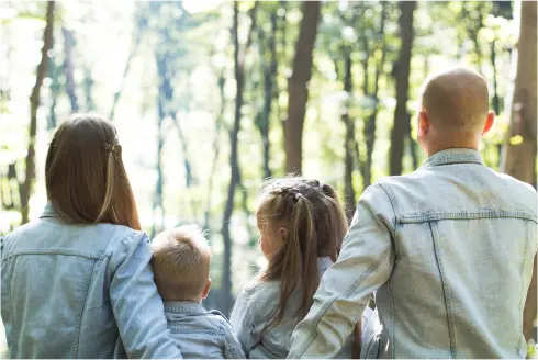 Family facing away from the camera with a a wooded background